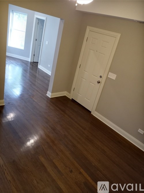 A room with a white door and wooden floors.