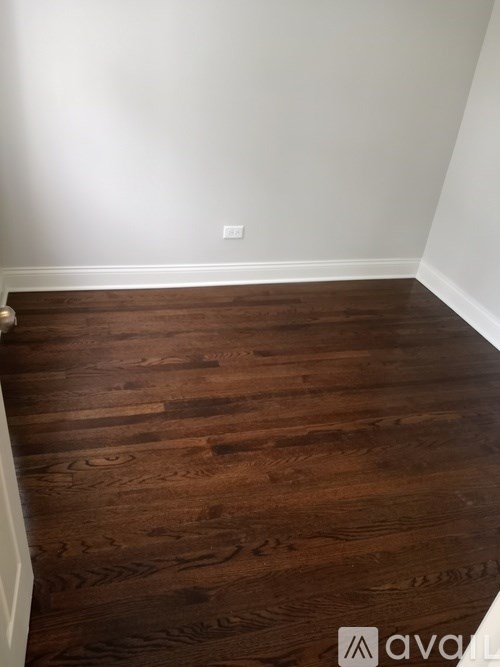 A room with wooden flooring and a white wall.