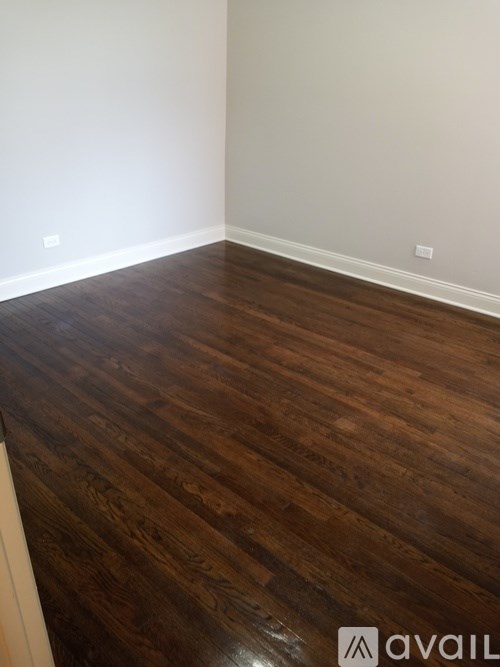 A room with wooden flooring and a white wall.