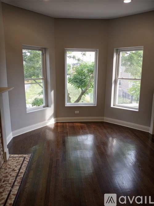 A room with wooden floors and three windows.