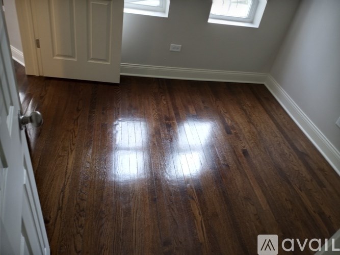 A room with wooden floors and a window letting in sunlight.
