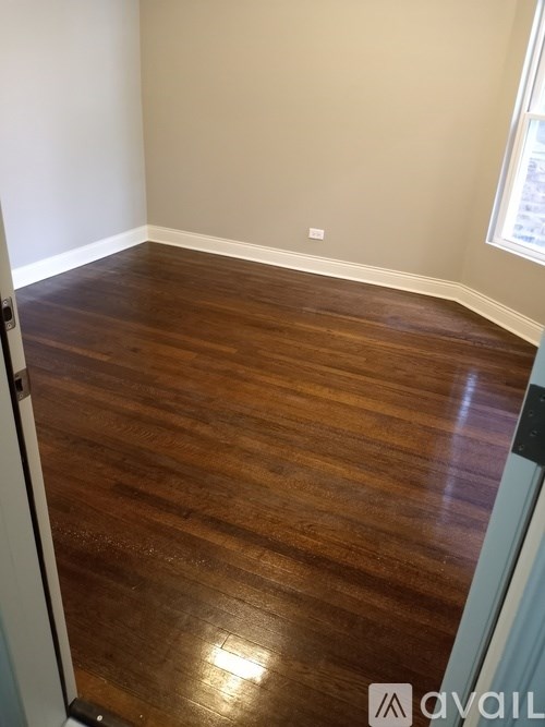 A room with wooden flooring and a window.