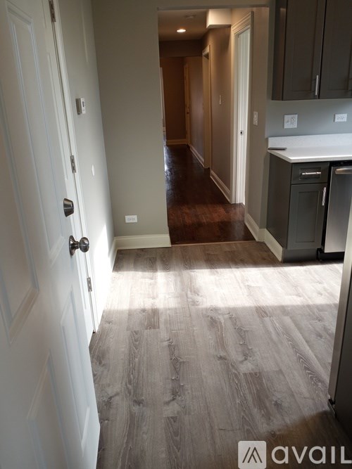 A hallway with a white door and a kitchen area with a stove and oven.