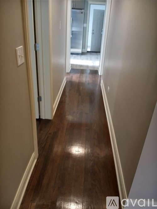 A hallway with wood flooring and white walls.