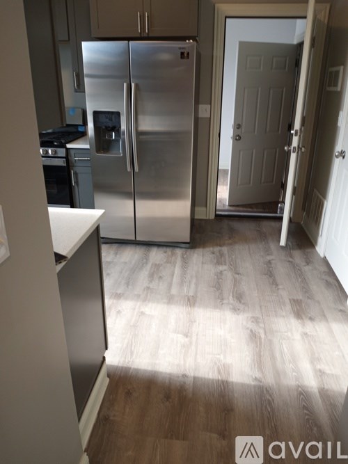 A kitchen with a refrigerator and a door leading to another room.