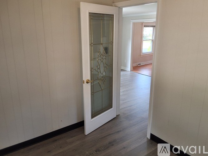 A white door with a glass panel is open to a hallway.