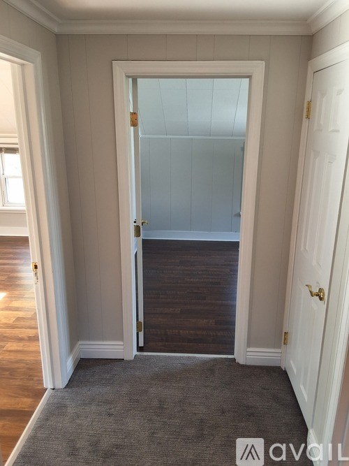 A room with a white door and a carpeted floor.