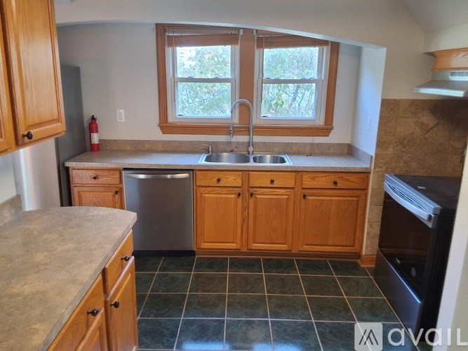 A kitchen with wooden cabinets and a stainless steel dishwasher.