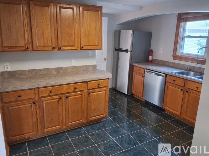 A kitchen with wooden cabinets and a tiled floor.