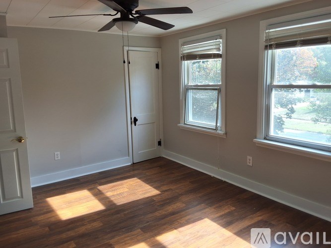 A room with a ceiling fan and two windows.