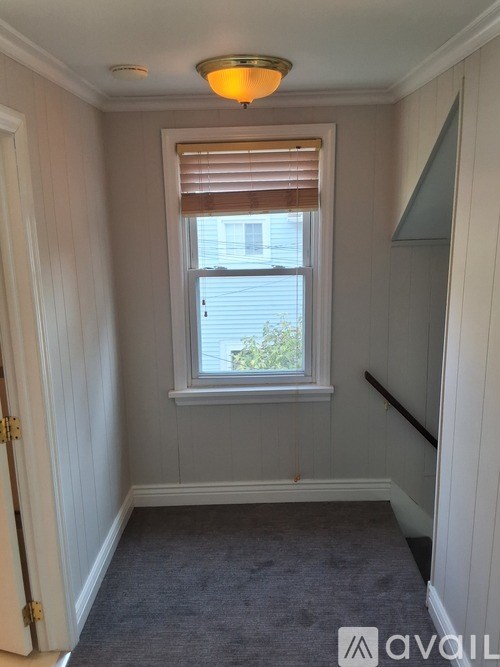 A room with a window and a carpeted floor.