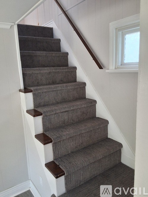 A staircase with a carpeted runner and wooden handrails.