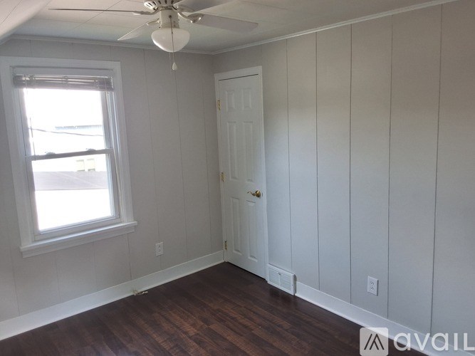 A room with a white door and a window with white blinds.