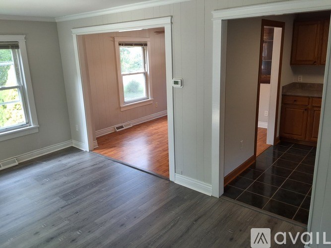 A room with a window and a door leading to a kitchen.