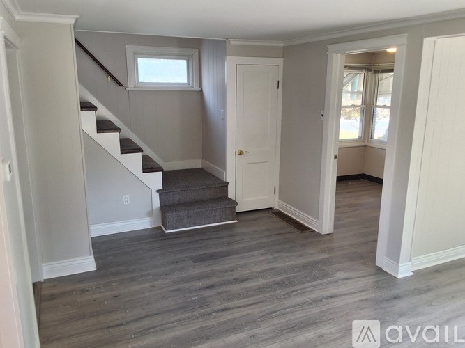 A room with a staircase and a door leading to another room.