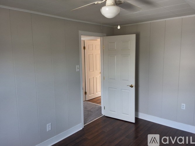 A room with a white door and a ceiling fan.