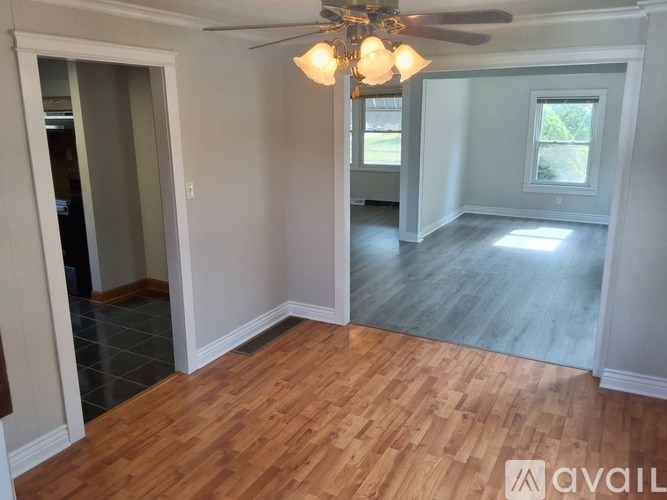 A room with wooden flooring and a ceiling fan with lights.