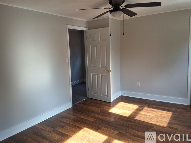 A room with a ceiling fan and wooden flooring.