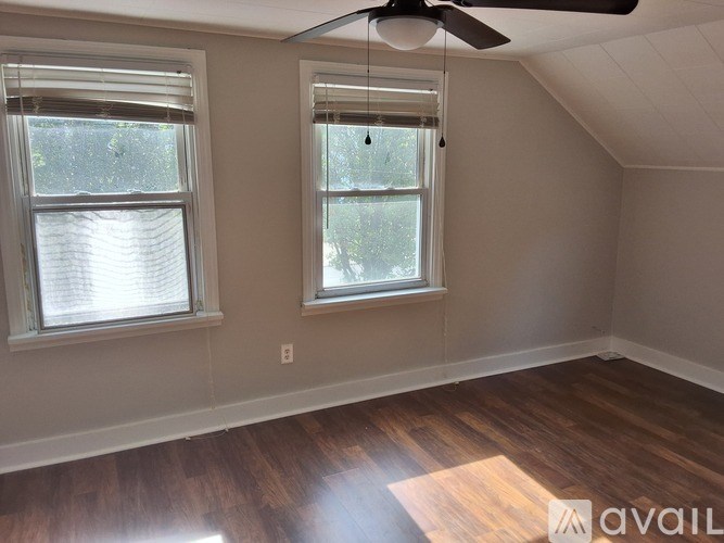 A room with a ceiling fan and two windows.