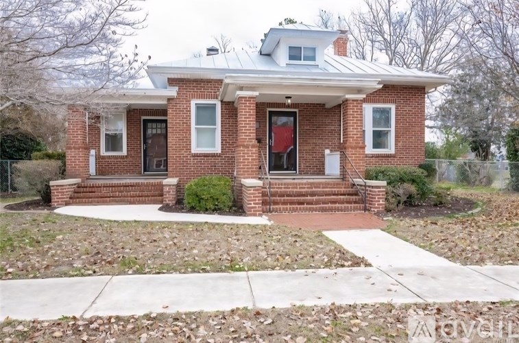 A red brick house with a white roof and a front porch.