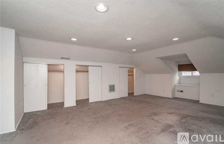 A spacious empty room with a window and a skylight.
