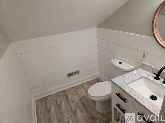 A bathroom with a toilet, sink, and wood paneling.