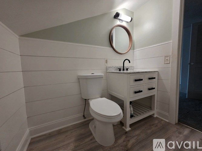 A bathroom with a toilet, sink, and mirror.