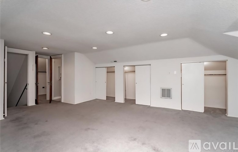 A spacious empty room with white walls and ceiling, and a few doors.