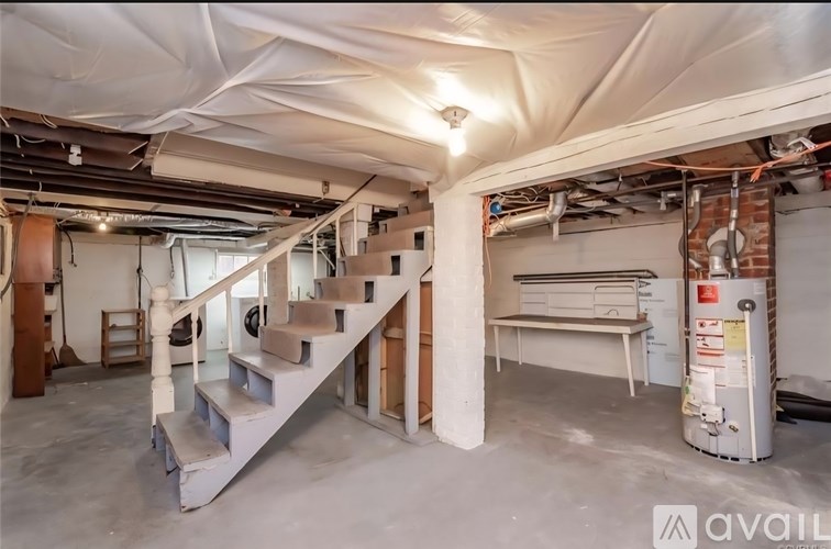 A spacious basement with a staircase, a bench, and a water heater.