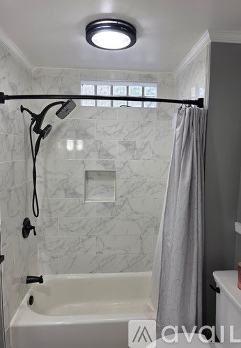 A white bathtub with a grey shower curtain in a bathroom.