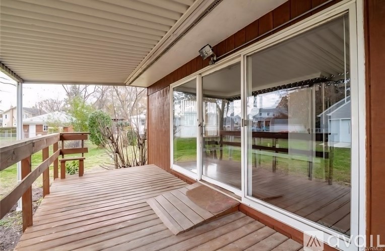 A deck with a sliding glass door leading to a backyard.