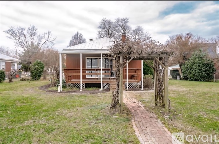 A house with a porch and a tree in front of it.