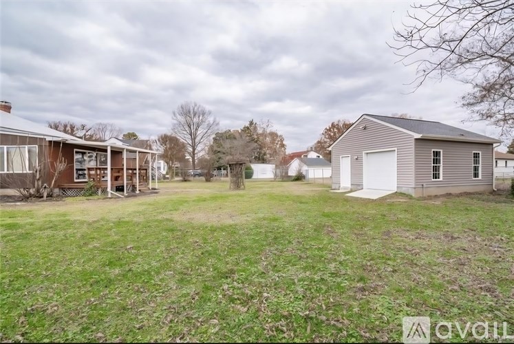 A grassy field with a house and a shed in the background.