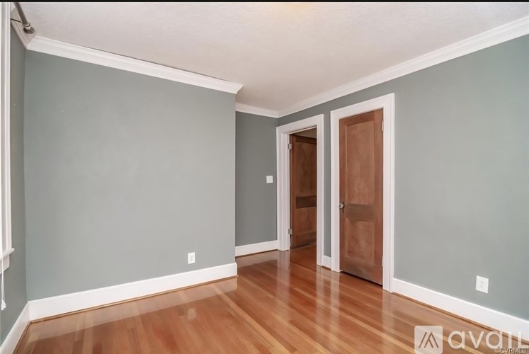 A room with wooden floors and a doorway leading to another room.