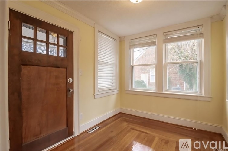 A room with a wooden door and two windows with blinds.