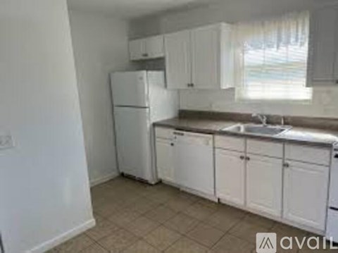 A kitchen with white cabinets and a white fridge.