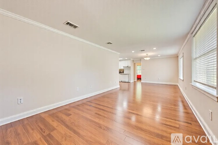 A room with wooden floors and white walls, with a window on the right side.