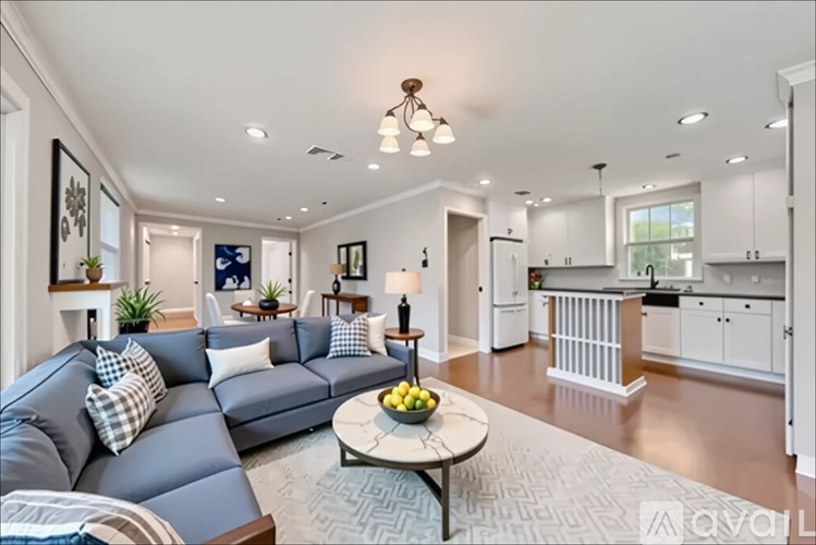 A living room with a grey sofa and a coffee table with a bowl of fruit on it.