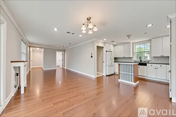 A spacious kitchen with white cabinets and a wooden floor.