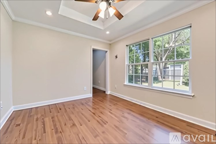 A room with a ceiling fan and wooden flooring.
