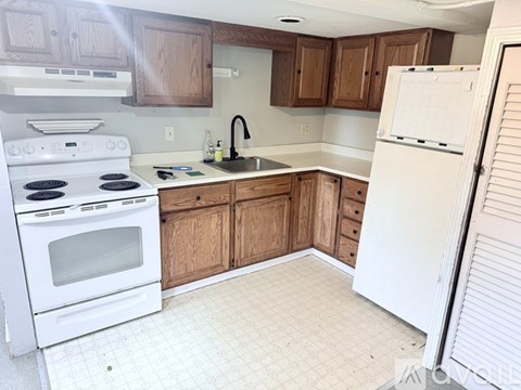 A kitchen with white appliances and wooden cabinets.