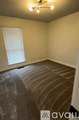 A room with a carpeted floor and a window with blinds.