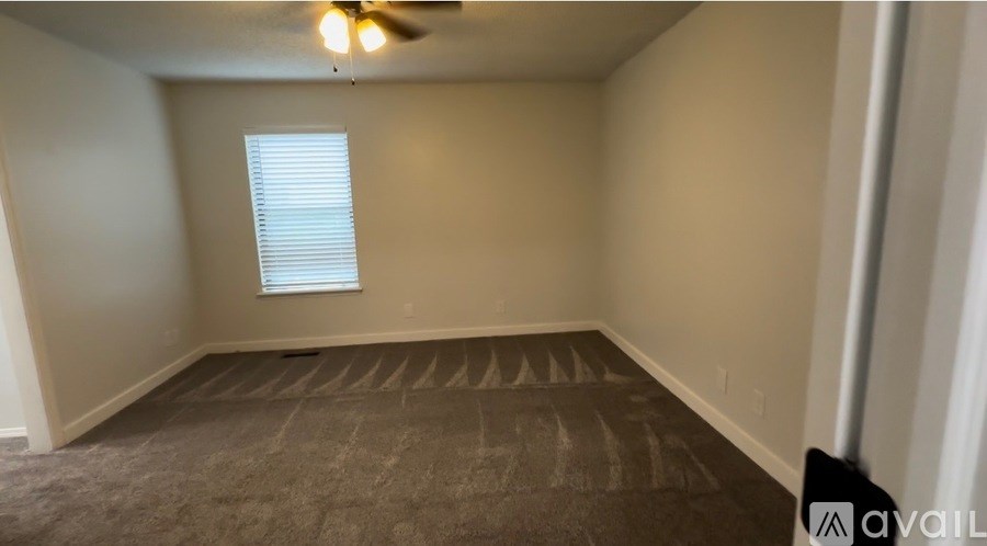 A room with a ceiling fan and a window with blinds.
