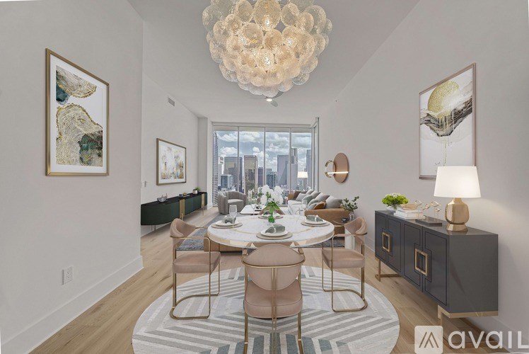 A dining room with a round table and chairs, a chandelier, and pictures on the wall.