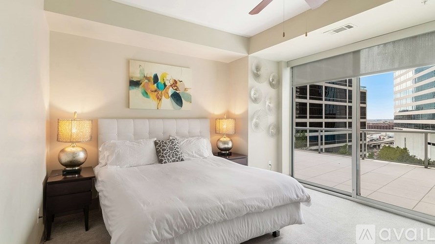 A bedroom with a large bed, two lamps, and a painting on the wall.