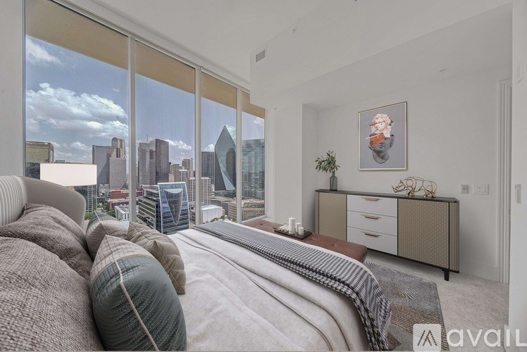 A bedroom with a large bed and a view of the city skyline.