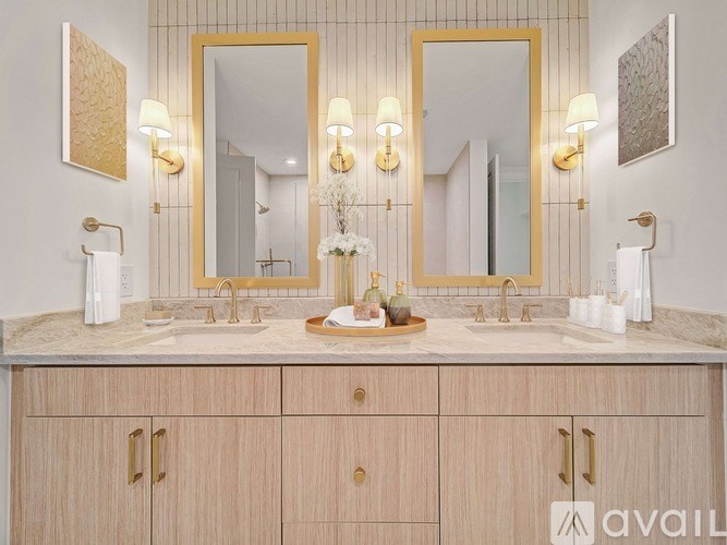 A bathroom with a marble countertop and two gold framed mirrors.