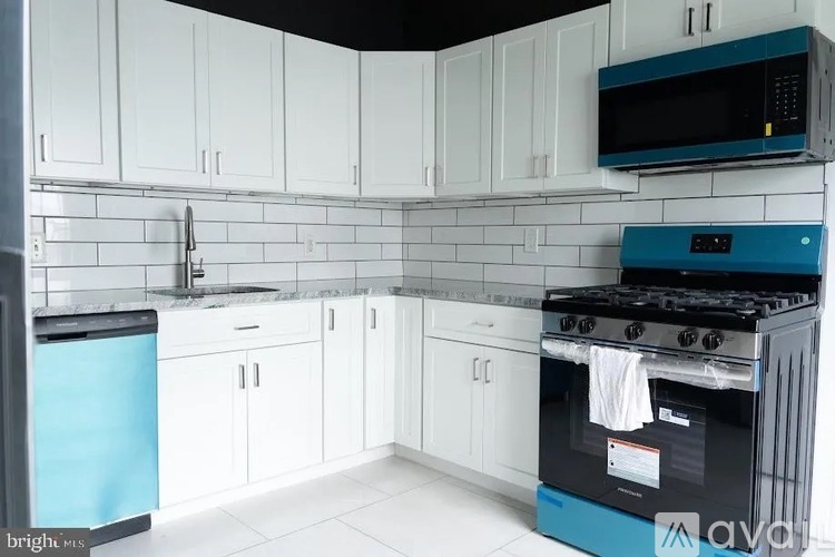 A kitchen with white cabinets and a blue dishwasher.