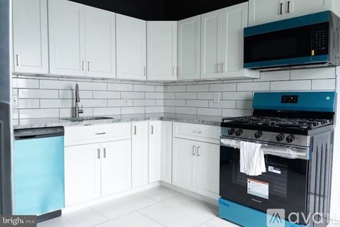 A kitchen with white cabinets and a blue dishwasher.