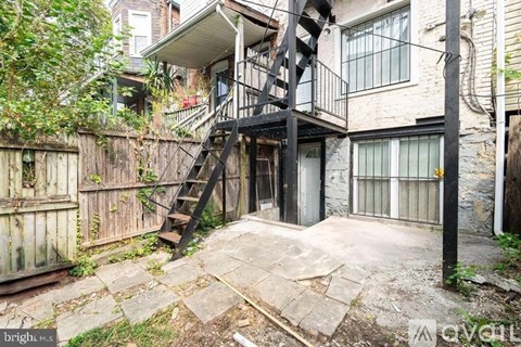 A dilapidated backyard with a wooden fence and a metal staircase.